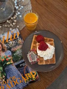 a plate of waffles with strawberries and whipped cream at Hotell Rådhuset in Lidköping