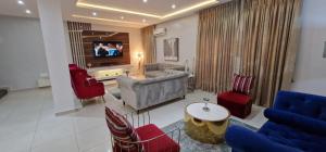 a living room with a couch and chairs and a tv at Luxury 3-Bed house in gated estate with pool Lekki in Maiyegun