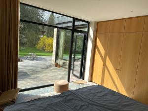 a bedroom with a large glass door with a view of a patio at Modern bungalow in forest area in Nærum