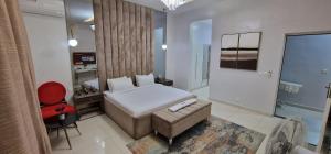 ein Schlafzimmer mit einem Bett, einem Stuhl und einem TV in der Unterkunft Luxury 3-Bed house in gated estate with pool Lekki in Maiyegun