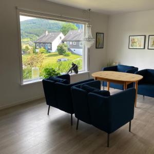 ein Wohnzimmer mit einem Tisch und Stühlen sowie einem großen Fenster in der Unterkunft Store Ringheim Apartment - Villa Hjadlane in Vossevangen