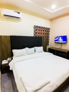 a bedroom with a white bed and a flat screen tv at Come Inn Hotel in Rubuchi