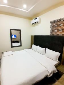 um quarto com uma cama branca e uma televisão na parede em Come Inn Hotel em Rubuchi
