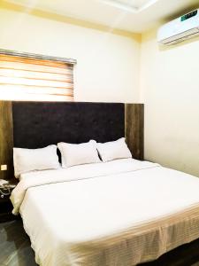 um quarto com uma grande cama branca e uma cabeceira preta em Come Inn Hotel em Rubuchi