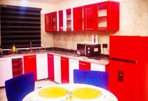 a kitchen with red cabinets and a table and blue chairs at 2bedroom Masters Apartment in Gwarinpa