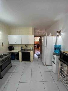 a kitchen with white tile floors and white appliances at Sua casa na praia in Caucaia