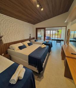 a bedroom with three beds and a piano in it at Pousada Lá em Casa in Barra Grande