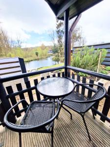 a table and chairs on a deck with a view of a river at Otter 2 HuntersMoon- Warminster-Wiltshire-Bristol in Warminster