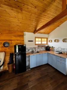 een keuken met een zwarte koelkast en een houten plafond bij Serenity Retreats Maciuca 