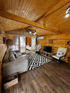 a living room with a couch and a television in a log cabin at Serenity Retreats Maciuca 