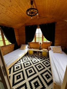 een slaapkamer met 2 bedden en een tapijt in een hut bij Serenity Retreats Maciuca 