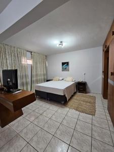 IKA Apart Hotel في برازيليا: غرفة نوم بسرير ومكتب وتلفزيون