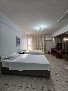 um quarto de hotel com duas camas e uma televisão em IKA Apart Hotel em Brasília