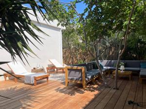 un patio con sofás y mesas en una terraza de madera en Villa dans son écrin de verdure, en La Ciotat