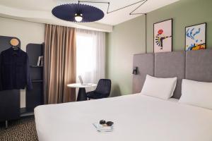 una camera d'albergo con un letto bianco e un tavolo di ibis Saint-Nazaire - Trignac a Trignac