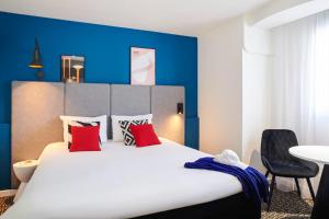 una camera da letto con un grande letto bianco con cuscini rossi di ibis Saint-Nazaire - Trignac a Trignac