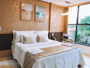 um quarto com uma cama grande com lençóis brancos e almofadas em HOTEL VIANA em Barra do Corda