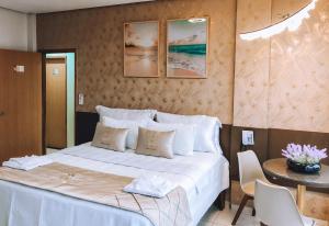 HOTEL VIANA في Barra do Corda: غرفة نوم بسرير ابيض مع طاولة وكراسي