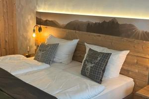1 cama con almohadas blancas y una foto en la pared en Hotel Auhof en Grossarl