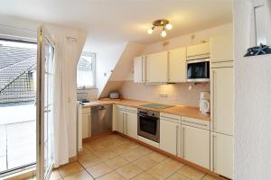 a small kitchen with white cabinets and a window at FeWo Ahoi - 73 qm maritime Gemütlichkeit auf zwei Ebenen in Ostseebad Koserow +6 photos