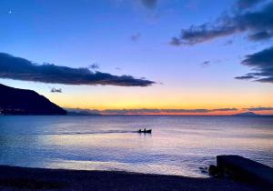 een zonsondergang over de oceaan met een boot in het water bij the Lighthouse in Castellammare di Stabia