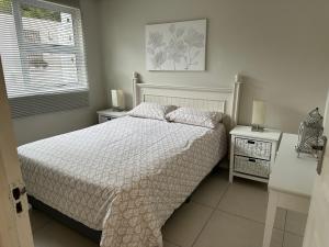 a white bedroom with a bed and two night stands at 2 Bedroom Apartment with Private Gym in Johannesburg