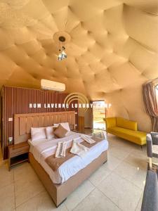 a bedroom with a large bed and a yellow couch at Rum Laverne Luxury Camp in Wadi Rum