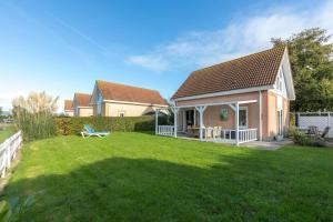 a house with a yard with a bench in it at Villa-Meerchen-Villa-mit-ueberdachter-Terrasse-800m-vom-Strand-entfernt in Kamperland