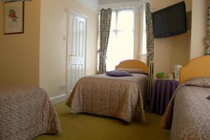 a hotel room with two beds and a window at Gatwick Turret Guest House in Horley