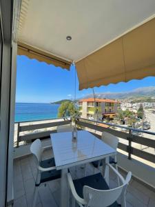 - une table et des chaises blanches sur un balcon donnant sur l'océan dans l'établissement George Apartments, à Himarë