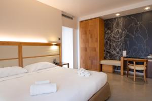 a bedroom with a large white bed and a desk at The Ziba Hotel & Spa in Peschiera del Garda