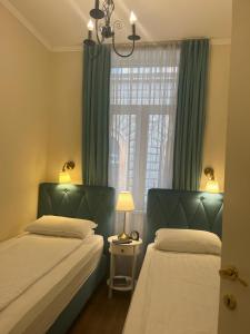 een slaapkamer met 2 bedden en een raam met groene gordijnen bij Aria Apartments Sarajevo in Sarajevo
