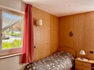 Villa Iris Asiago - giardino e parcheggio في أسياجو: غرفة نوم صغيرة بها سرير ونافذة