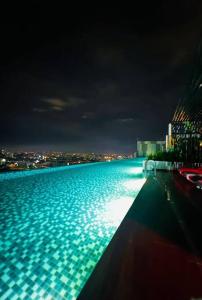 a swimming pool at night with a city in the background at The Horizon Ipoh Infinity Pool 17th floor in Ipoh