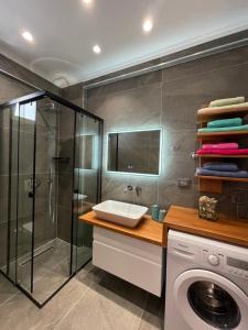 ein Bad mit einer Dusche und einer Waschmaschine in der Unterkunft George Apartments in Himarë