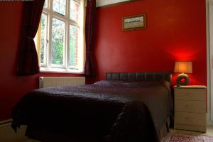 a red bedroom with a bed and a window at Gatwick Turret Guest House in Horley