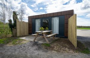 ein winziges Haus mit einem Tisch und einem Zaun in der Unterkunft B&B/Tiny House Bij Zee in Stellendam