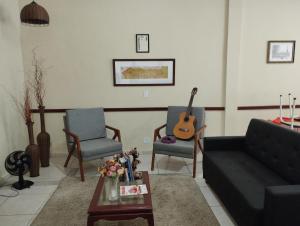 un soggiorno con un divano, 2 sedie e una chitarra di Nostra Cuesta Hostel a Botucatu
