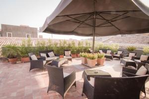 une terrasse avec des chaises, des tables et un parasol dans l'établissement Dimora De Mauro, à Catane
