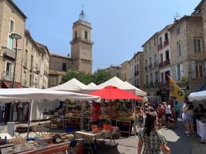 einen Markt in einer Stadt mit einem Uhrturm in der Unterkunft Ma petite étoile sur les toits in Pézenas