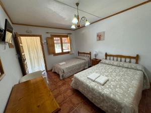 a bedroom with two beds and a table and a window at El retiro hotel rural in Moratalla