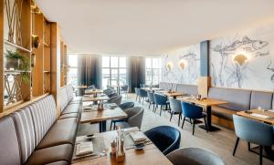 um restaurante com mesas de madeira e cadeiras azuis em Lindner Hotel Boltenhagen, part of JdV by Hyatt em Boltenhagen