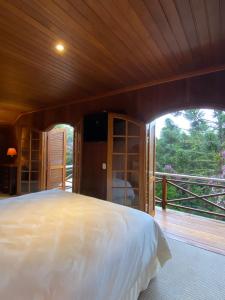 um quarto com uma cama grande e uma janela grande em Tília Pousada de Charme em Campos de Jordão