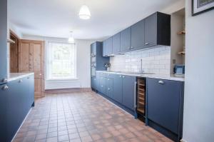 uma cozinha com armários azuis e piso em azulejo em Hill House - 4 Bedroom Holiday Home - Llanrhidian em Llanrhidian
