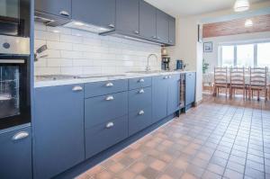 a kitchen with blue cabinets and a tile floor at Hill House - 4 Bedroom Holiday Home - Llanrhidian in Llanrhidian