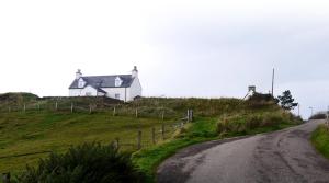 a house sitting on top of a hill next to a road at Cnoc Ard in Scourie