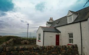 a white house with a stone wall and a table at Cnoc Ard in Scourie
