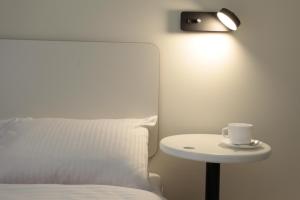 a bed with a cup on a table with a lamp at Ultramarinn Hotel in Odesa