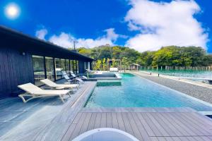 a swimming pool with white lounge chairs next to a building at MOKU ISESHIMA ーl モク伊勢志摩 lー in Shima