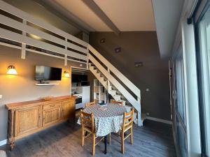 a dining room with a table and a loft bed at Rêve de plage in Camiers